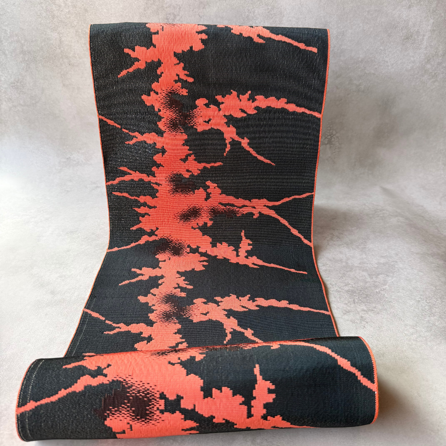 Full view of black and coral abstract woven obi fabric bolt