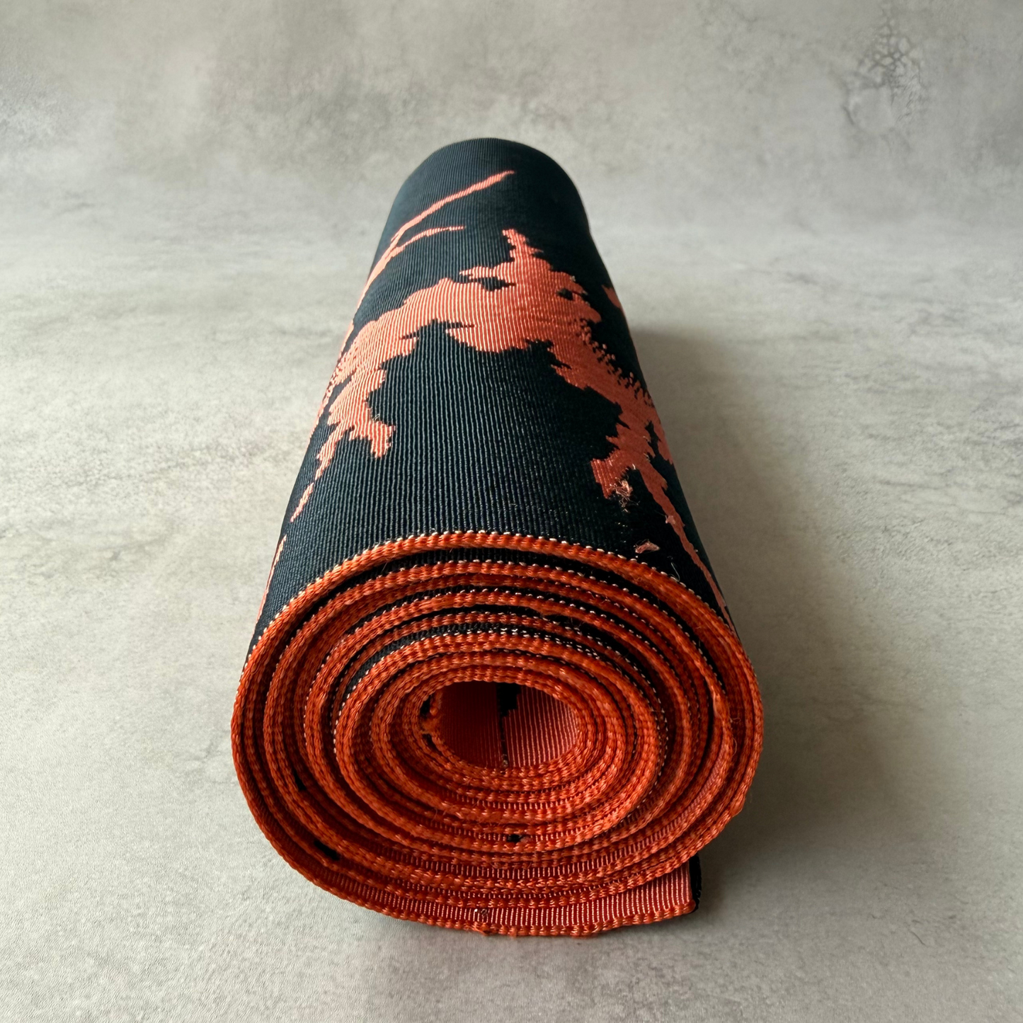 End view of rolled pre-owned coral and black obi fabric bolt