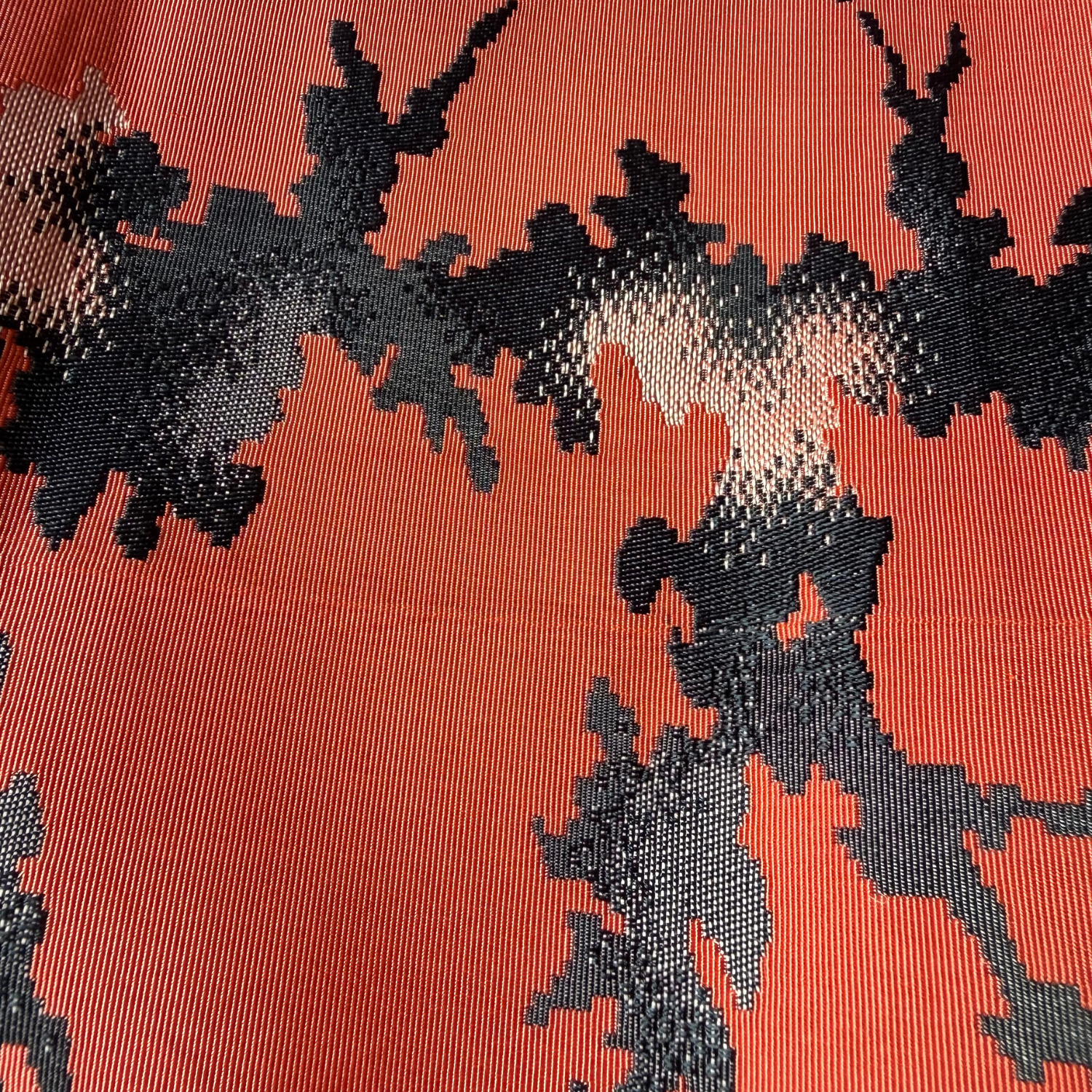 Close-up showing sheen and woven texture of coral abstract obi fabric